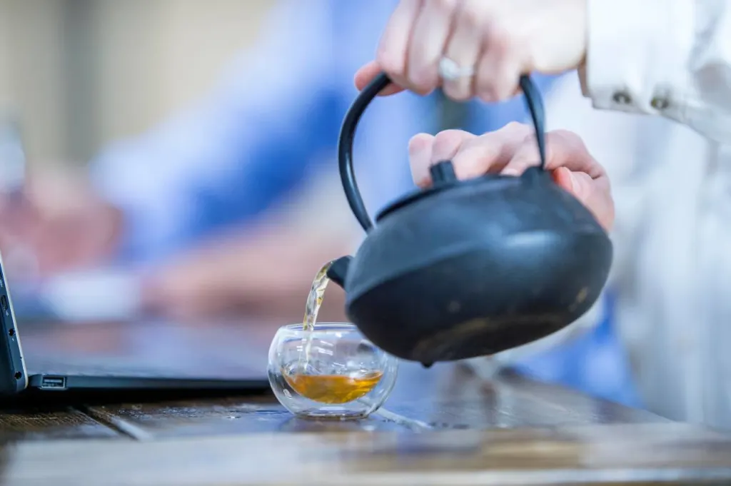 Woman taking a break from work pouring tea at her desk